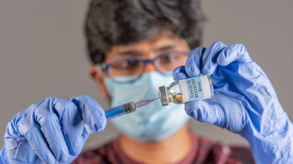 Close up of doctor hands holding covid-19 vaccine booster shot with syringe | FDA OKs Pfizer booster dose for At-Risk Americans | featured
