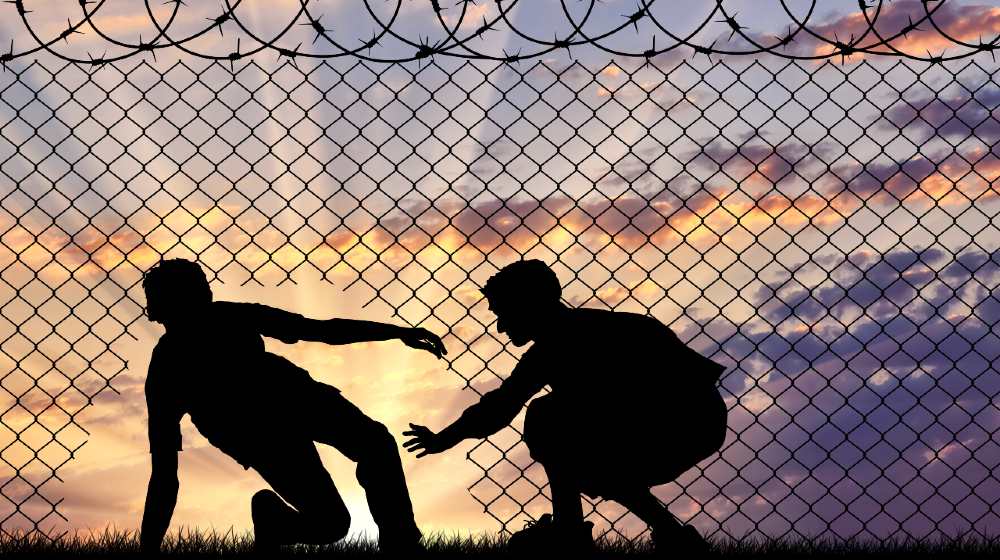 Concept of the refugees. Silhouette of refugees crossed the border illegally through the hole in the fence-Biden’s Border Policies-SS-Featured
