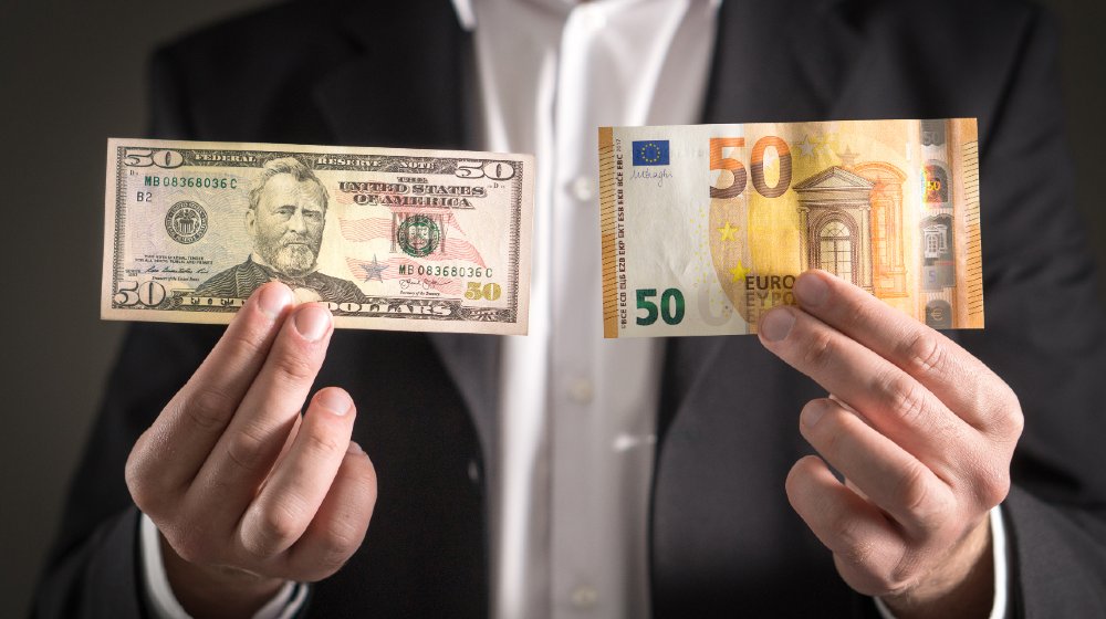 Dollar vs euro. Business man in suit holding 50 banknote and bill in both currency in hand-weak us dollar-ss-featured