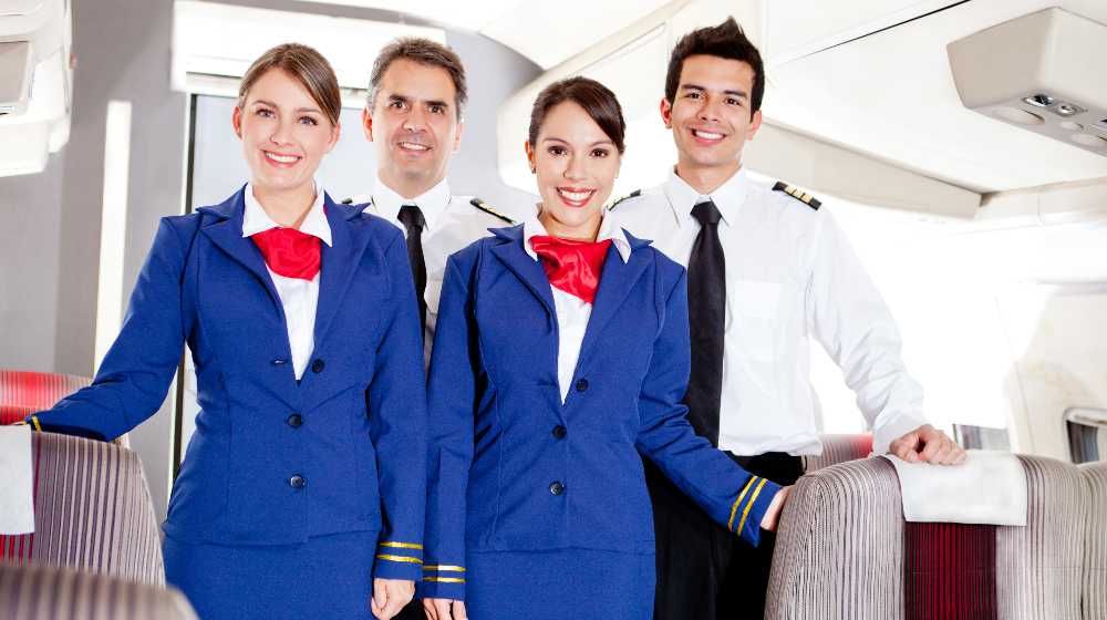 Friendly cabin crew in an airplane smiling | Delta Flight Attendants Will Now Get Paid for Boarding Duties | featured