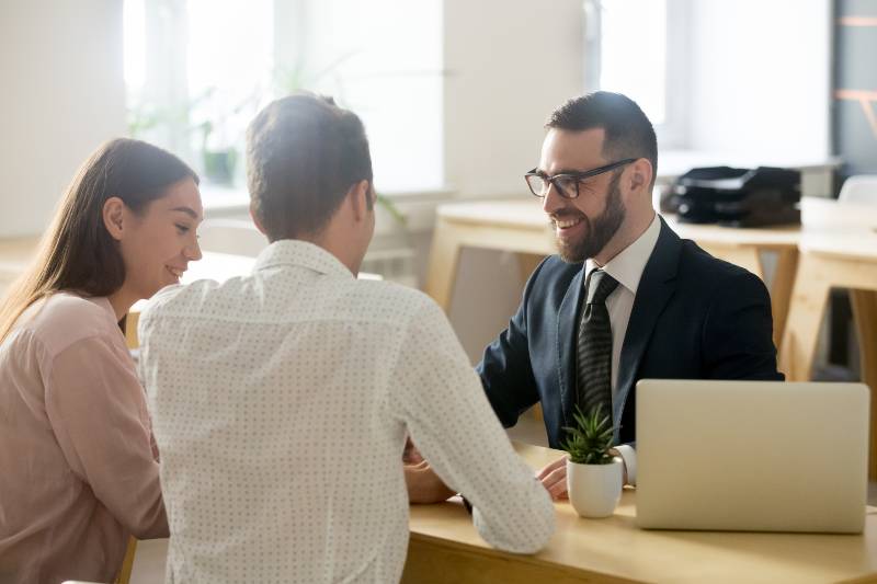 Friendly lawyer or financial advisor in suit consulting young couple-financial sector