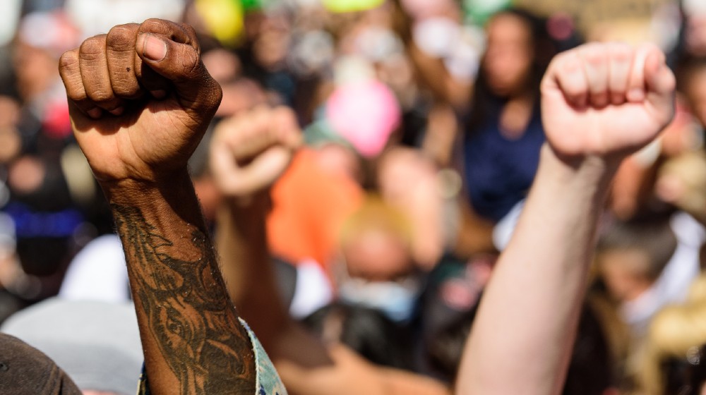 Hands of white and black people during a protest against racism in America | Florida Senate Approves Anti-Riot Bill | Featured