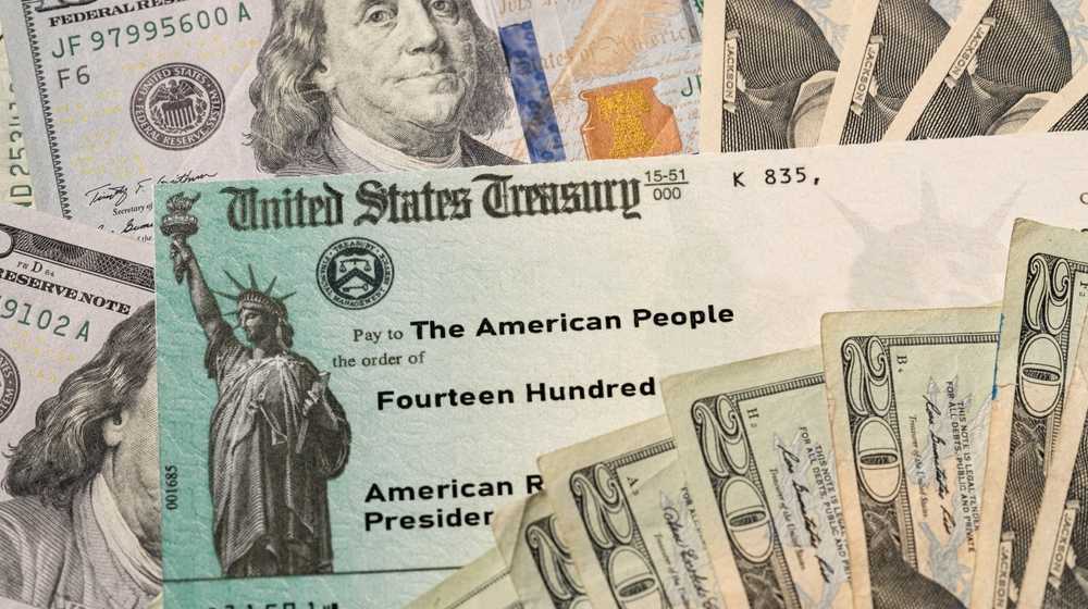Illustation of dollar bills and a stimulus check-The $1400 Stimulus Checks Could Arrive Starting Next Week Under COVID-19 Relief Package -ss-Featured