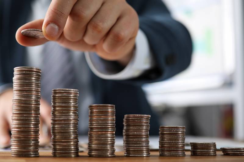 Male hands in suit stack coins on table, saving | save money