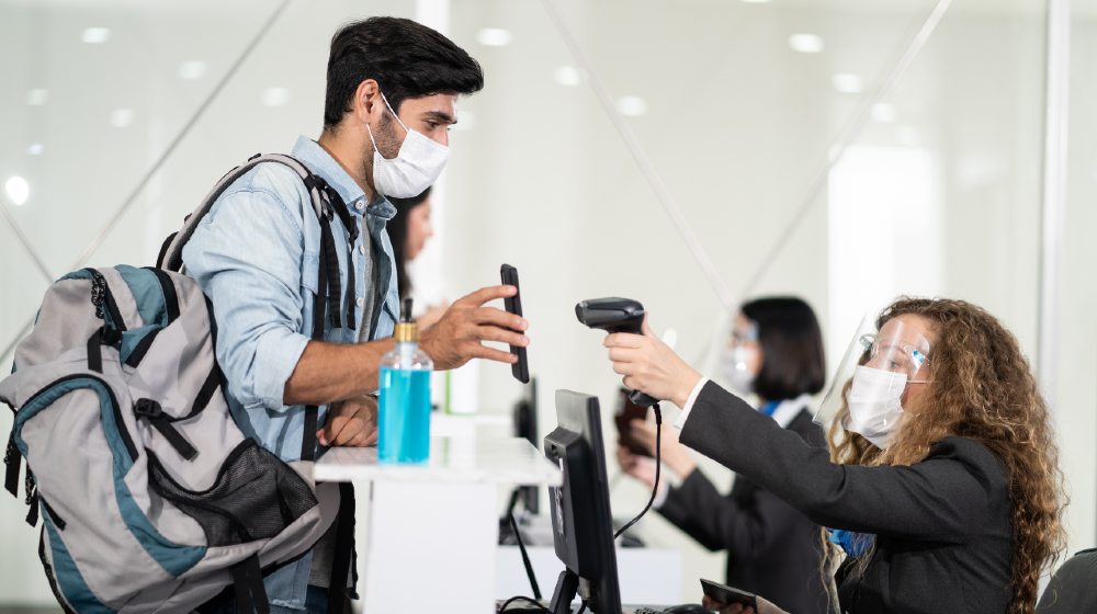 Male traveler shows phone to female officer at airline check in counter for issue airplane ticket boarding pass-Airline Travel Pass-ss-featured