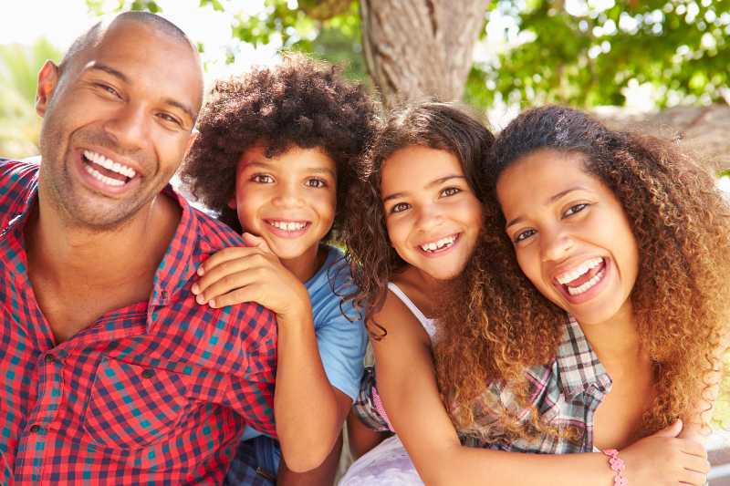 Parents Giving Children Piggyback Ride Outdoors | American Families