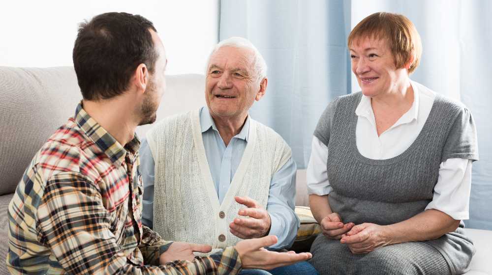 Parents and adult son enjoying quiet evening together at home | 50% of American Parents Still Support Their Adult Children | featured