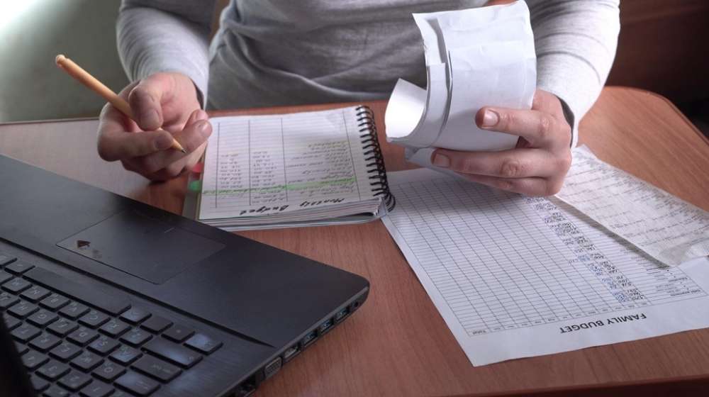 Person doing finances-Household Debt Rises to $14.6 Trillion Due to Increase in Mortgage Loans-ss-Featured