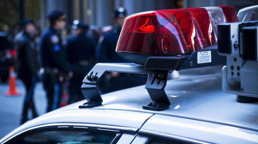 Police Car Lights with Group of Policemen on the Background | Louisville Police Chief Fired Following Death of Unarmed Black Man | Featured