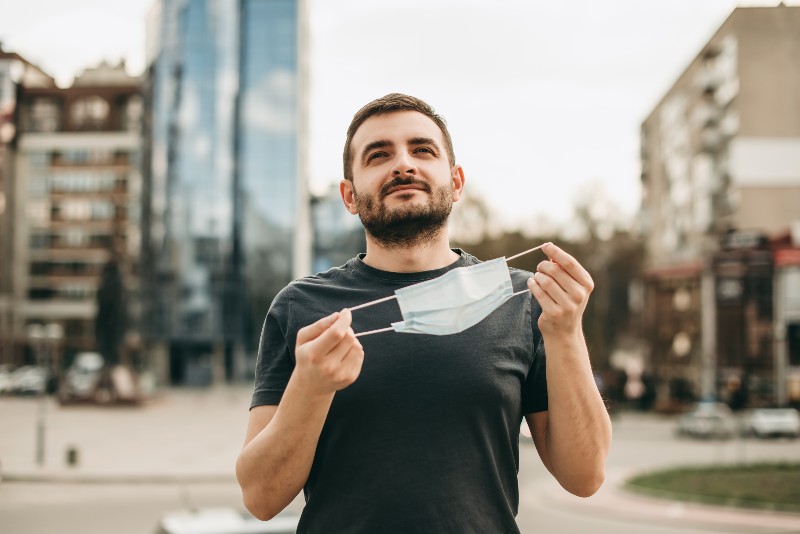 Portrait happy brunette man drops his medical surgical mask | Drop Mask Mandates Now