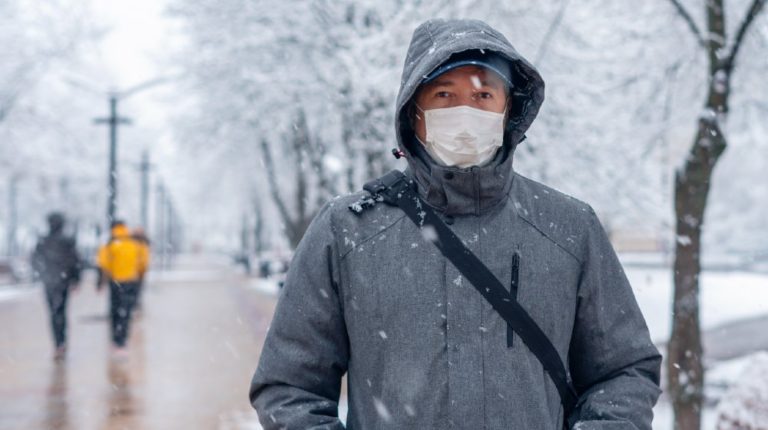 Portrait of a Man Wearing a Medical Protective Mask on his Face in Winter | Brace Yourselves: COVID-19 Winter Is Coming | Featured