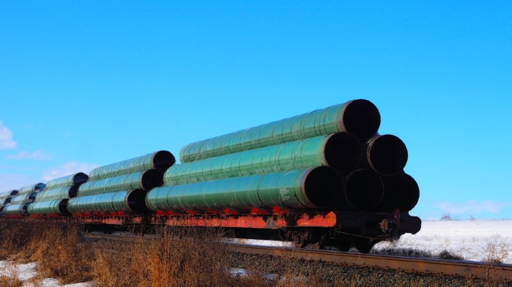 Railway flatcar loaded with large diameter pipe destined for use on the Trans Mountain Pipeline-21 States-ss-featured