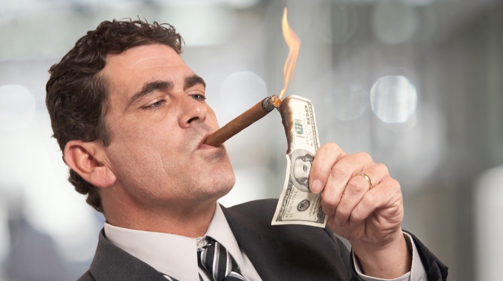 Rich businessman lighting cigar with $100 dollar bill-Trickle Down Economics Doesn't Work-ss-featured