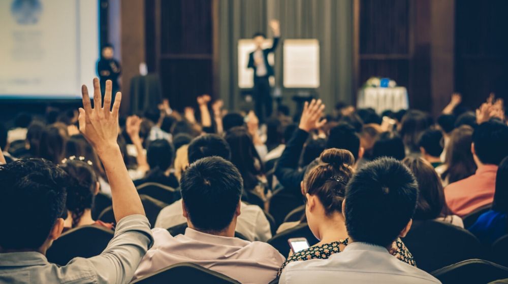 speaker on stage with number of attendees | House Approves Bill That Lets Illegal Immigrants Seek Damages From Employers | Featured