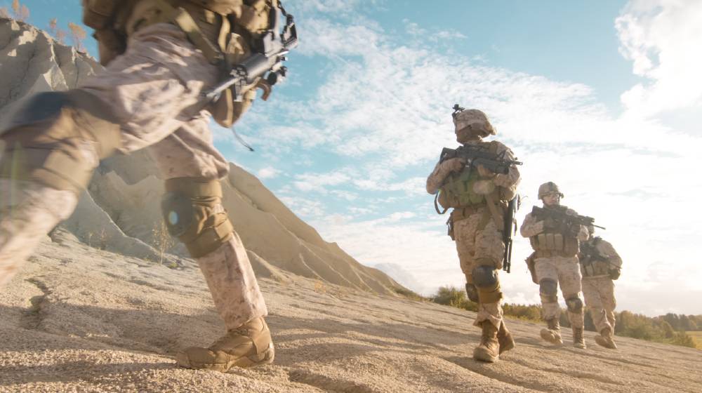Squad of Fully Equipped and Armed Soldiers Moving in Single File in the Desert | As Taliban Advances, Biden Defends Afghanistan Pullout | featured