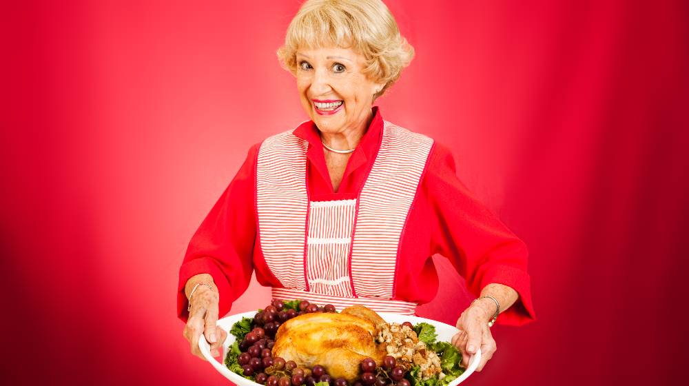 Sweet grandmother holding a beautifully cooked turkey dinner | Man Attends 6th Thanksgiving Dinner Despite Getting Wrong Invitation | featured