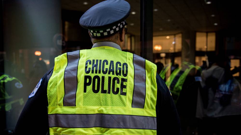 The back of a Chicago police officer controlling the crowd at a rally downtown in Chicago | Chicago Cops Turn Back on Mayor After 2 Officers Shot | featured