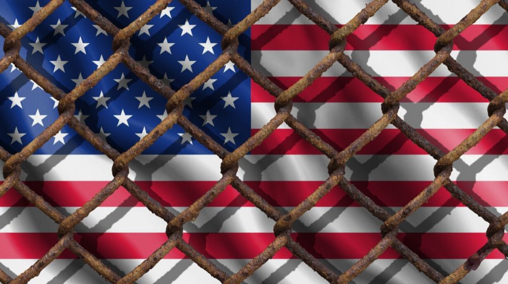 US flag in barricade | Expanded U.S. Travel Ban Affecting Six More Countries Goes into Effect | Featured