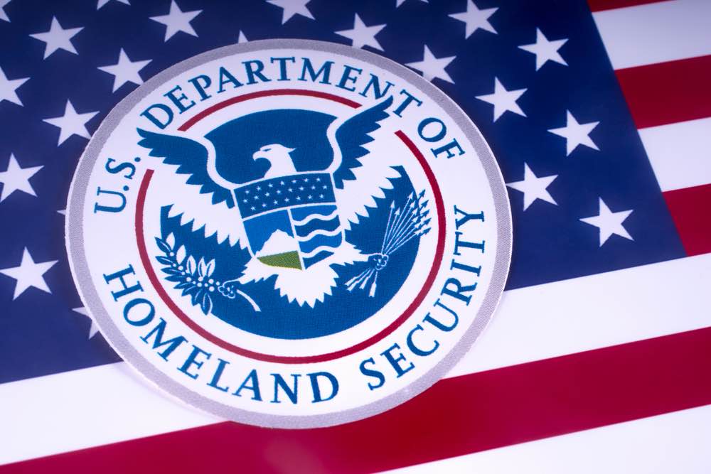 The symbol of the US Department of Homeland Security pictured over the USA Flag | Alejandro mayorkas