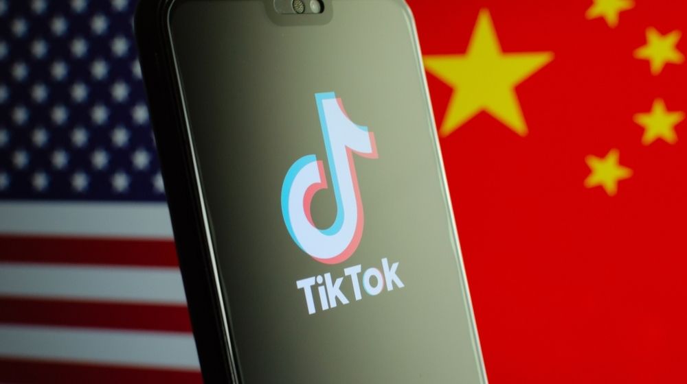 TikTok App Logo on a Smartphone Screen and Flags of China and United States on the Background | President Trump Bans TikTok and WeChat from the US, Unless Companies are Sold within 45 days | Featured