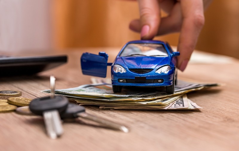 Toy car in hand, keys and money on table-auto loan