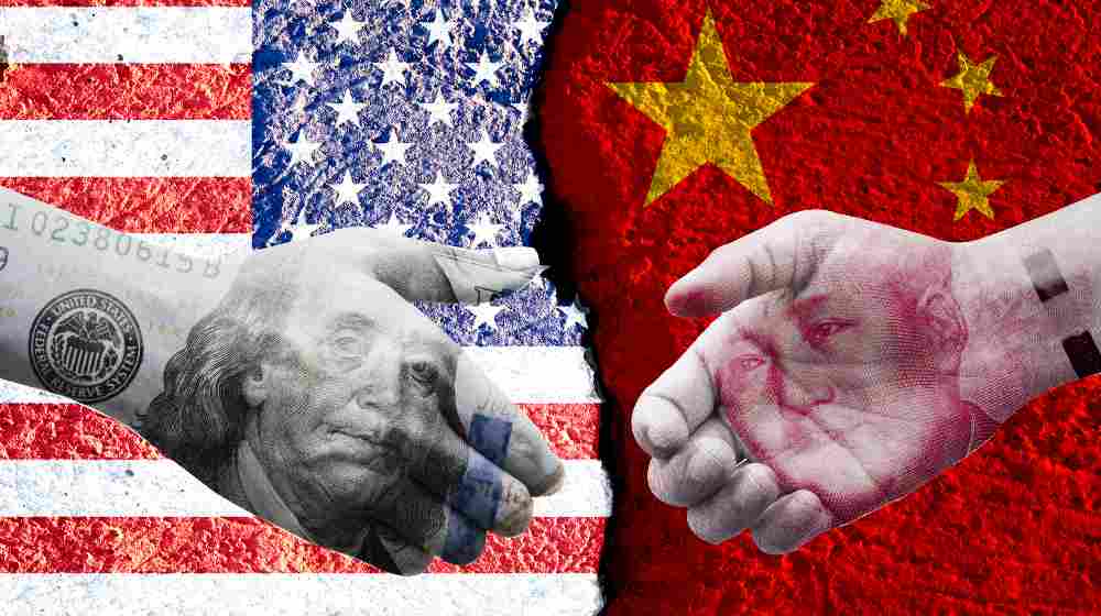 US dollar and China Yuan banknote print screen on handshake with both flags countries | China Didn’t Buy $200 Billion Worth of US Goods It Said It Will | featured