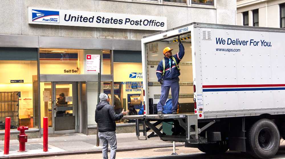 USPS postman on a mail delivery truck in New York | Postmaster Says US Postal Service Ready for the Holiday Rush | featured
