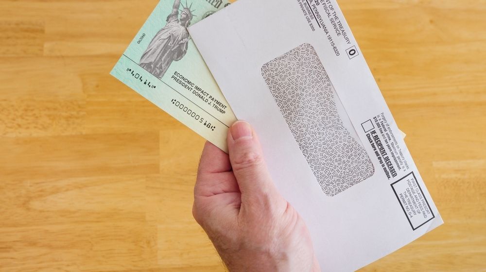 Hand Holding Stimulus Check for Coronavirus COVID-19 Pandemic Relief | Democrats Play Political Games While Americans Suffer | Featured