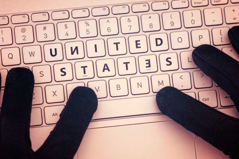 United States inscription on laptop keyboard. Hacker man using a laptop attacks the web | US Companies Alerted to Russian Cyberattacks
