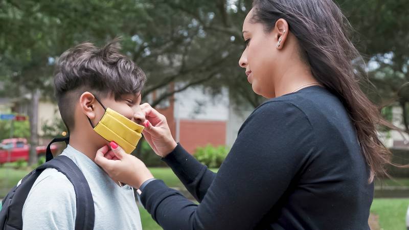 Waiting for the school bus to arrive this mom makes sure her son has his mask on | More States Dropping School Mask Mandates