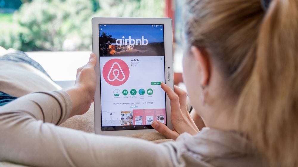 Woman Installing Airbnb Application on Lenovo Tablet | Airbnb Restricts Some Guests Under 25 from Booking in Their Local Area | Featured