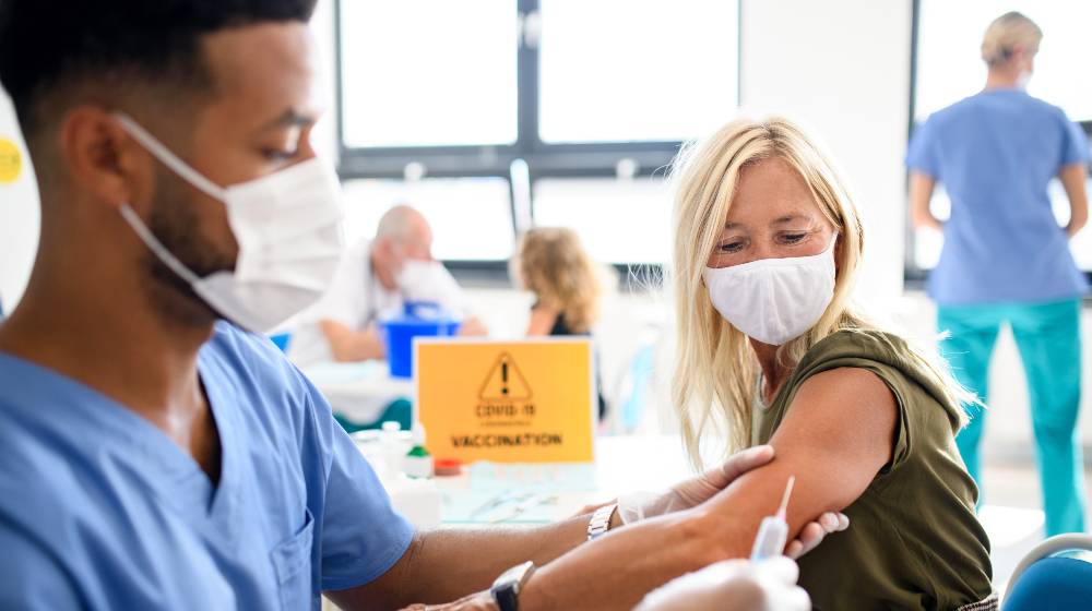 Woman with face mask getting vaccinated, coronavirus, covid-19 and vaccination | COVID-19 Vaccine Protection Wanes After Six to Eight Months | featured