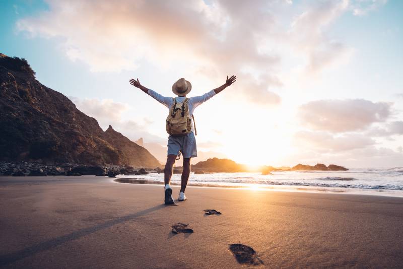 Young man arms outstretched by the sea at sunrise-Create Your Own Reality