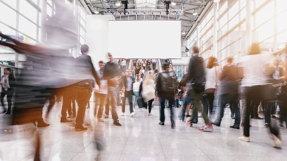 Anonymous People at a Trade Fair | NSSF Announces Cancellation of 2021 SHOT Show Amid Rising COVID Cases | Featured