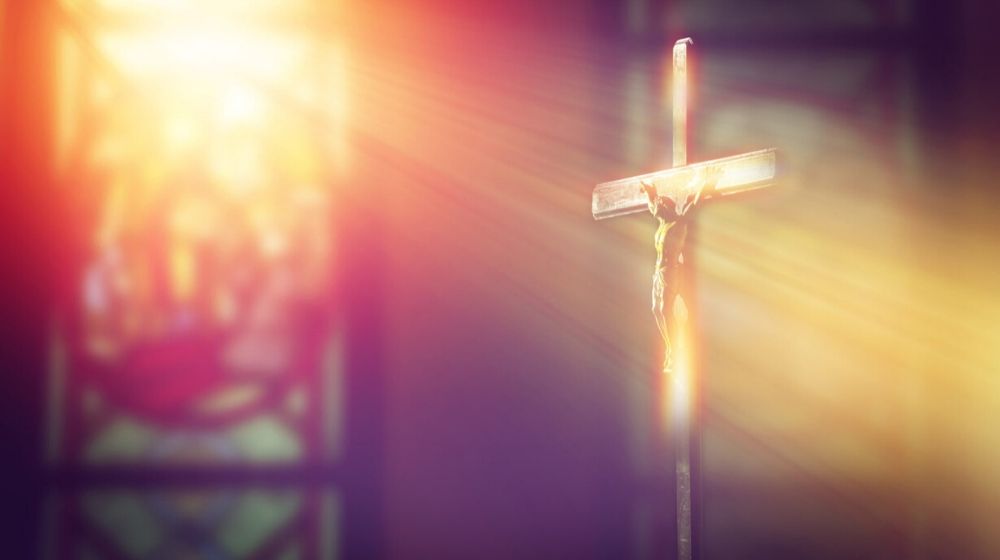 cruxifix with ray of light from the stained glass | Churches Offer Drive-Thru Prayer Amid Coronavirus Shutdowns | Featured