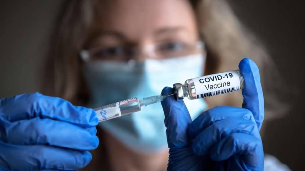 healthcare worker extracting COVID-19 vaccine with syringe-COVID-19 Vaccines Drop Risk of Serious Illness by 80%-ss-Featured