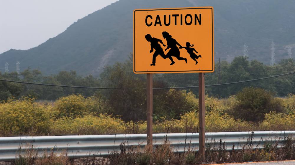 highway sign showing family crossing | Abbott Orders Texas National Guard To Arrest Migrants | featured