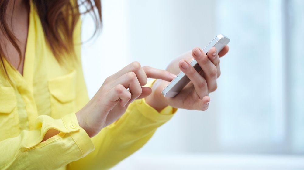 Close Up of Teenage Girl Hands with Smartphone at Home | “I Checked In” App Allows Contact Tracing While Alleviating Privacy Concerns | Featured