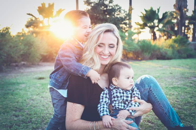 woman holding baby sitting on green grass field under sunset-US Birth Rates