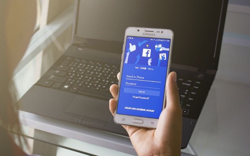 Woman Holding Smartphone Display Facebook App | Facebook Features Licensed Music Videos on Platform | Featured